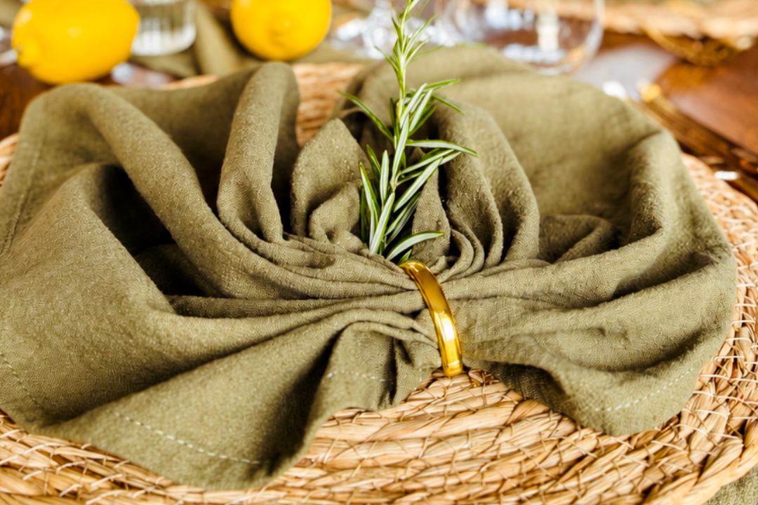Tischgedeck mit Tellern, Besteck und gefalteter Serviette auf einem eleganten Tisch.